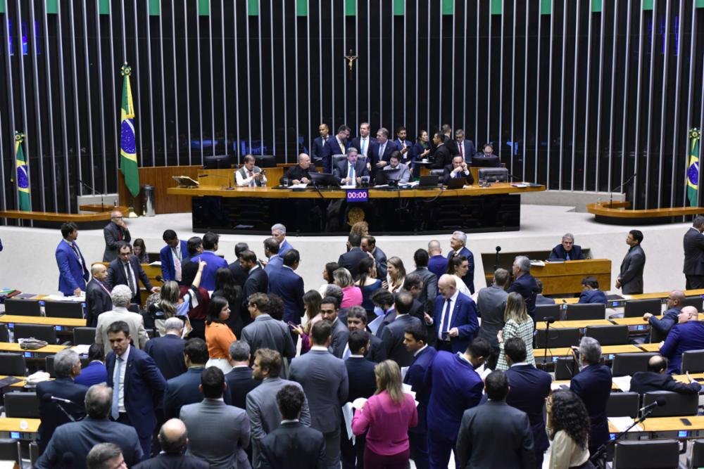 Reunião no plenãrio da Câmara dos Deputados em auditório com fundo escuro e mesa comprida de madeira à frente, para a votação do PL das Fake news em 25 de abril de 2023