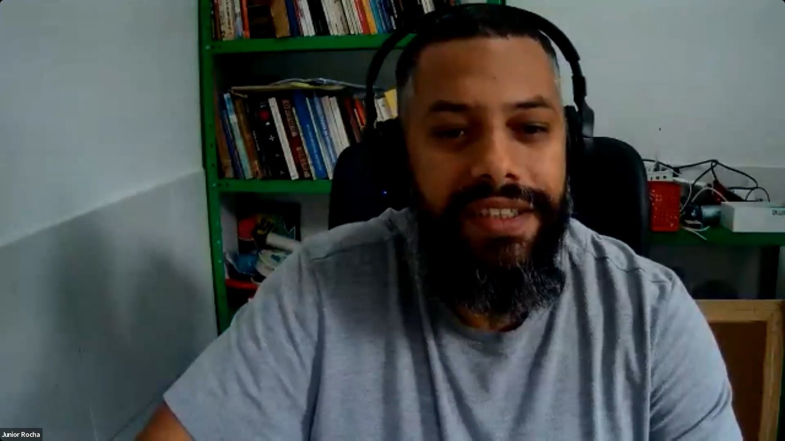 Junior Rocha homem moreno de barba e cabelos castanhos e fones de ouvido flala sobre ferramentas de tecnologia em reunião online